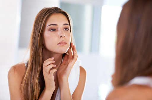 Concerned woman inspecting her jaw in the mirror